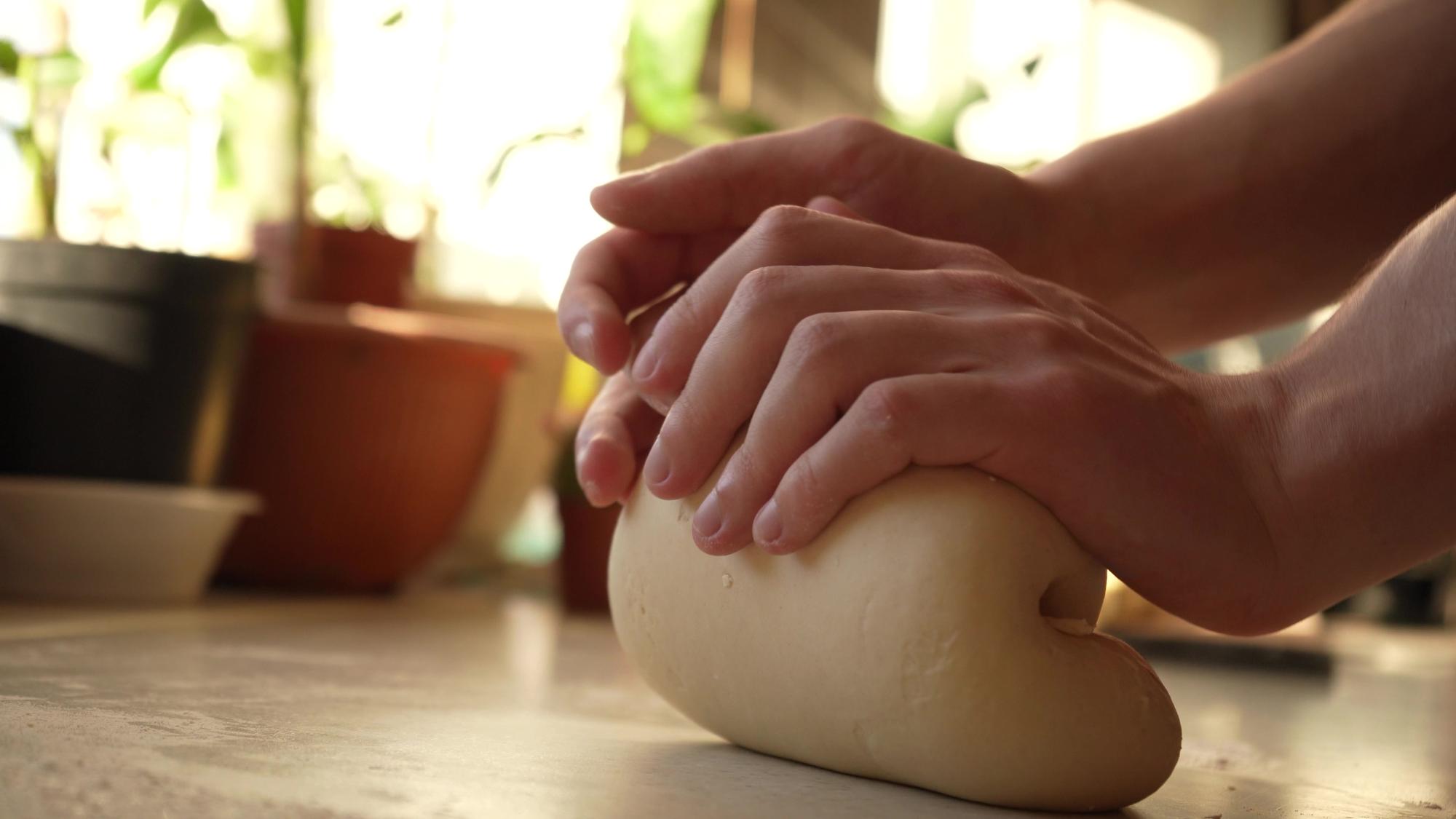 Hands kneading dough on wooden table