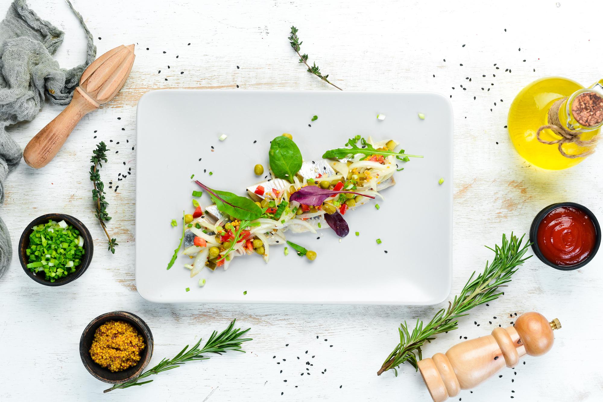 Chef arranging plated dish with herbs and sauces